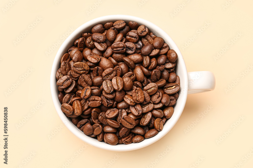Cup with aromatic coffee beans on pale yellow background