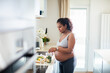 © Baba Images - Young pregnant latina woman preparing a salad in the kitchen