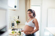 © Baba Images - Young pregnant latina woman preparing a salad in the kitchen