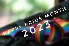 Happy Pride Month 2023 With Blurred Rainbow Wristband And Flag Background, Concept For LGBT Community Celebrations In Pride Month, June, Around The World.