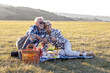 © pucko_ns - Senior couple enjoying a delightful picnic. The couple has a relaxed and contented expression  as they share a bottle of wine and a delicious spread of food.