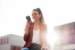 © Westend61 - Smiling businesswoman text messaging through smart phone at sunny day