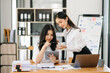 © Nuttapong punna - Two Asian businesswoman discuss investment project working and planning strategy with tablet laptop computer in office.