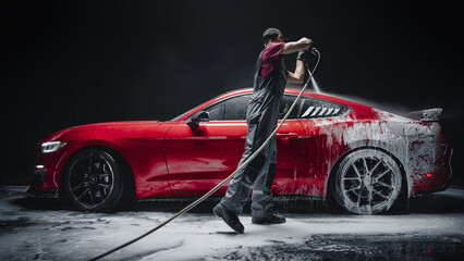  Car Wash Specialist Using Pressure Washer to Rinse a Red Modern Sportscar. Adult Man Washing Away Dirt, Preparing a Tuned Car for Detailing. Creative Cinematic Photo in Studio