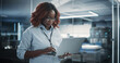 © Gorodenkoff - Portrait of a Technological Software Engineering Department Manager Standing and Using a Laptop Computer. African Female Looking in the Distance and Thinking while Working in the Office