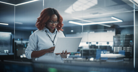 Aufkleber - Portrait of a Technological Software Engineering Department Manager Standing and Using a Laptop Computer. African Female Looking in the Distance and Thinking while Working in the Office