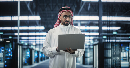 Aufkleber - Portrait of a Middle Eastern Data Center Administrator Wearing Traditional White Clothes, Using Laptop Computer in a Modern Technological Server Farm Facility. Arab Cybersecurity Expert at Work