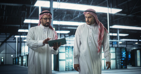 Poster - Middle Eastern Computer Engineer and Cybersecurity Specialist Work in Server Room, Talk, Perform System Maintenance Check with Laptop Computer. Specialists Doing Database Diagnostics in Data Center