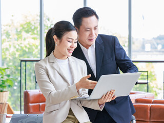 Asian professional successful female businesswoman secretary employee showing information strategy data via laptop notebook computer to male businessman manager in formal business suit in living room