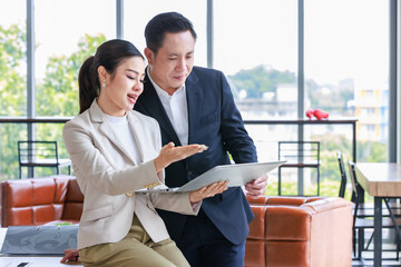 Asian professional successful female businesswoman secretary employee showing information strategy data via laptop notebook computer to male businessman manager in formal business suit in living room