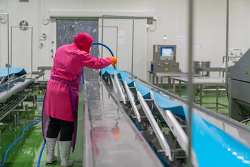Worker spray water on conveyor after finishing his daily job.