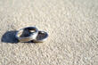 Silver wedding rings at the beach in the sand with copy space