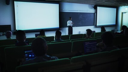 Leinwandbilder - Young University Professor Explaining the Importance of Branding and Marketing Campaigns to a Group of Diverse Multiethnic Students in a Dark Auditorium. Female Teacher Showing Business Charts Data