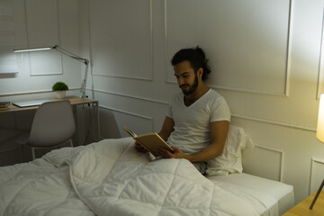 Wall Mural - Handsome latin man reading before sleeping