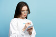 © Maria Vitkovska - Smart student studying, learning language, exam preparation isolated on blue background, education concept. Pensive woman, writer wearing eyeglasses  holding notebook, taking notes, copy space