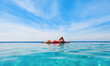 © Tropical studio - Happy girl have fun on summer beach holiday. Young woman relaxing at edge of infinity swimming pool with sea view from hill top. Healthy family lifestyle, summer travel with kids on tropical islands.
