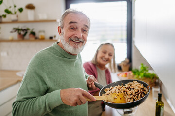 Wall Mural - Senior couple cooking together in their kitchen.