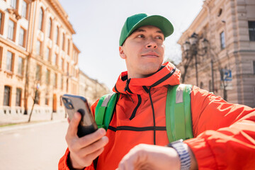 A satisfied courier is a man delivering a food order to the office to a client using an app for delivery.