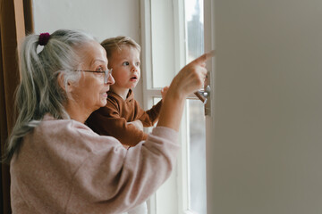 Grandmother with her little grandson looking out of the window.