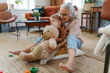 Wall Mural - Grandmother cuddling her little grandson with bear toy.