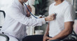© Kritdanai - Doctor use stethoscope, checking up heart beat, auscultation in doctor office at hospital. Patient worker has to get medical checkup every year for her health or