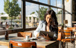 © Luis - Woman using a digital tablet while sitting in a coffee shop.