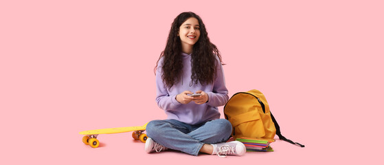 Wall Mural - Female student with mobile phone, backpack and skateboard on pink background