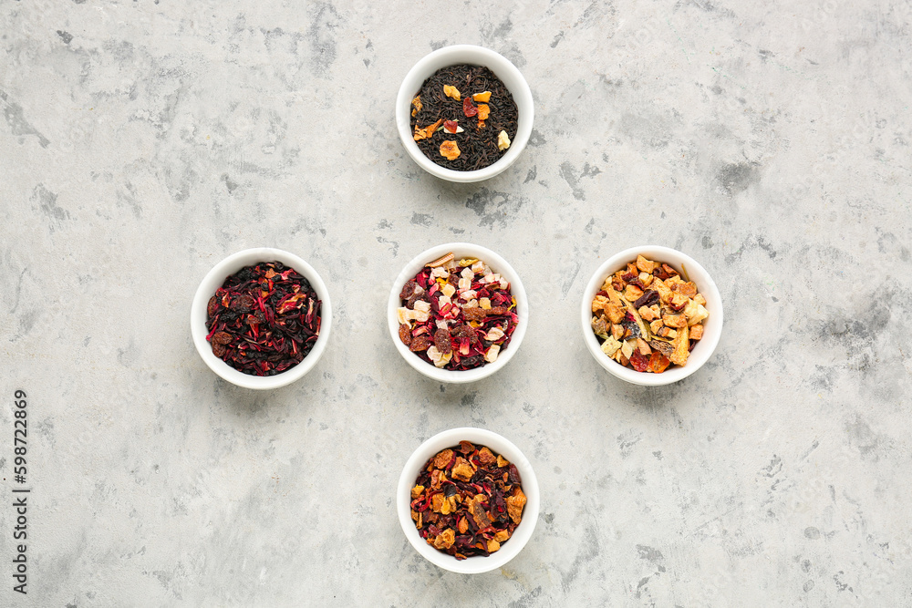 Bowls with different dried fruit tea on grey grunge table