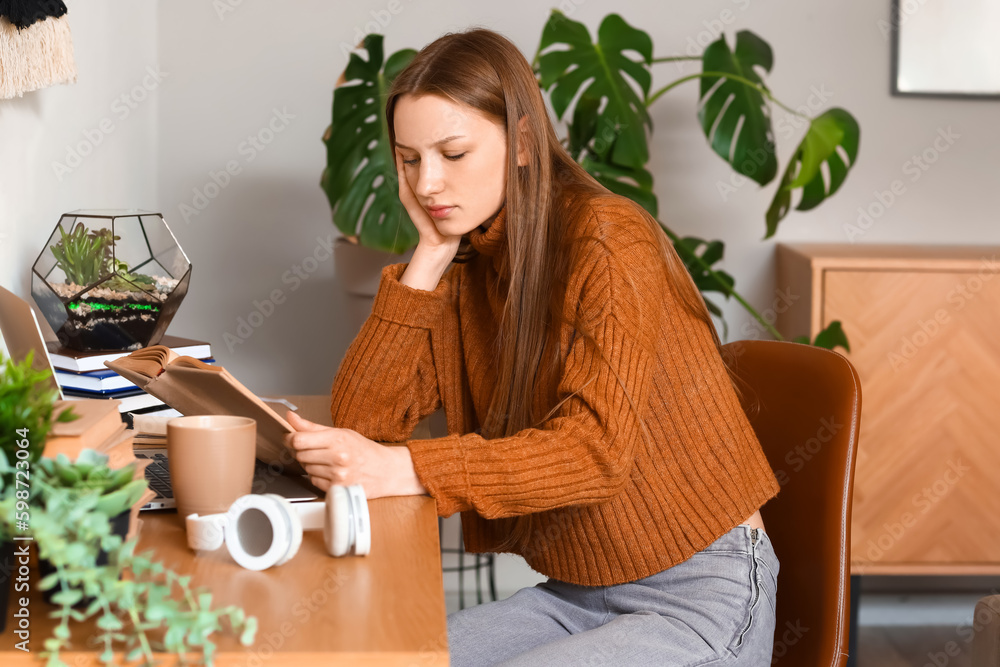 Female student reading book at home