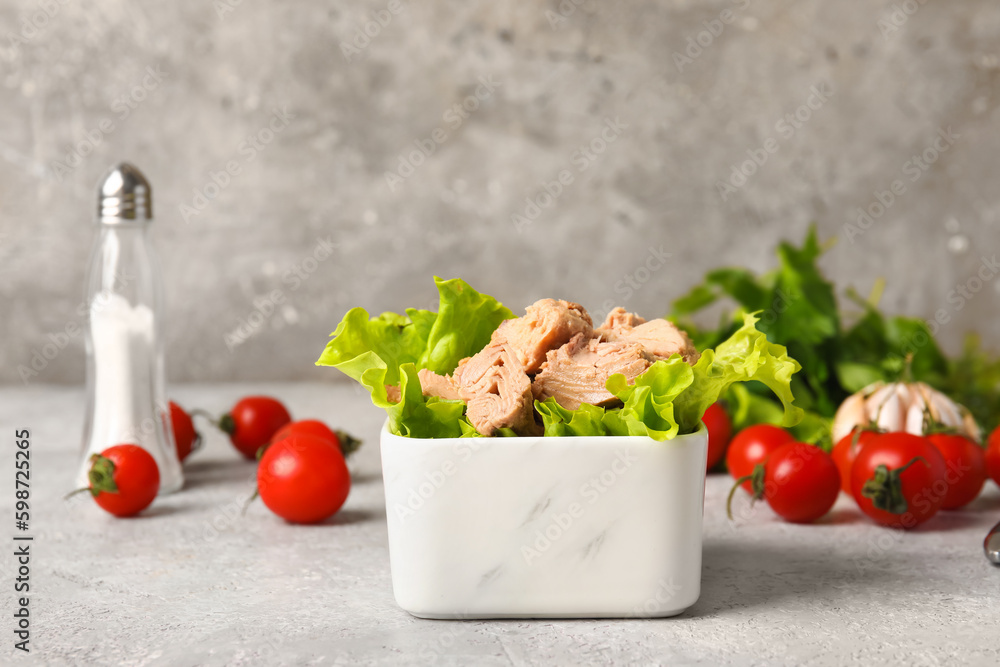 Bowl with delicious canned tuna and lettuce on white table