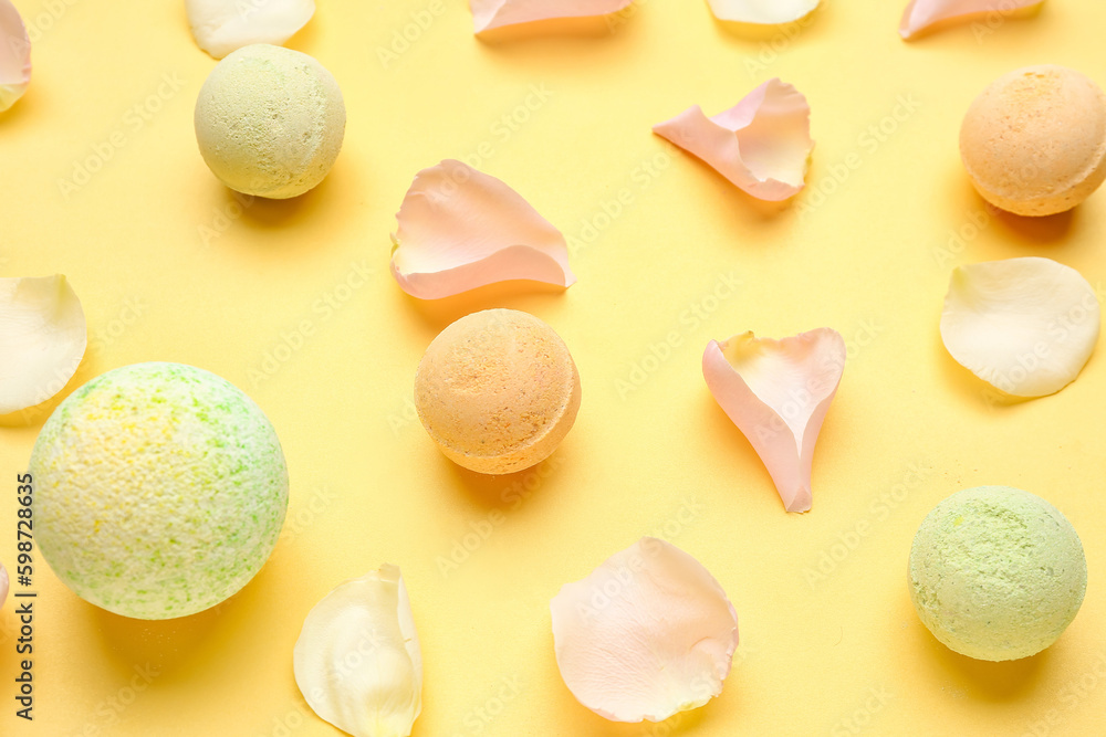 Bath bombs with floral petals on yellow background