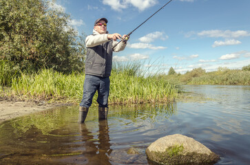 Wall Mural - Man catching fish, pulling rod while fishing.