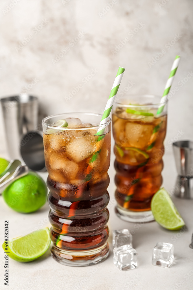 Glasses of cold Cuba Libre cocktail on light background