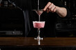 © Rabizo Anatolii - Bartender is pouring pink Clover club alcoholic cocktail in the glass. Bartender mixes egg white, lemon, dry vermouth and gin to prepare the Clover club cocktail.