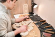 © Мар'ян Філь - A young guy is engaged in his favorite hobby - artistic wood carving, he holds in hands different chisels for wood carving and chooses which one is better for this work