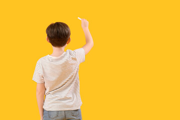 Sticker - Little boy drawing with chalk piece on yellow background, back view. Children's Day celebration