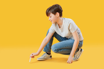 Sticker - Little boy drawing with chalk piece on yellow background. Children's Day celebration