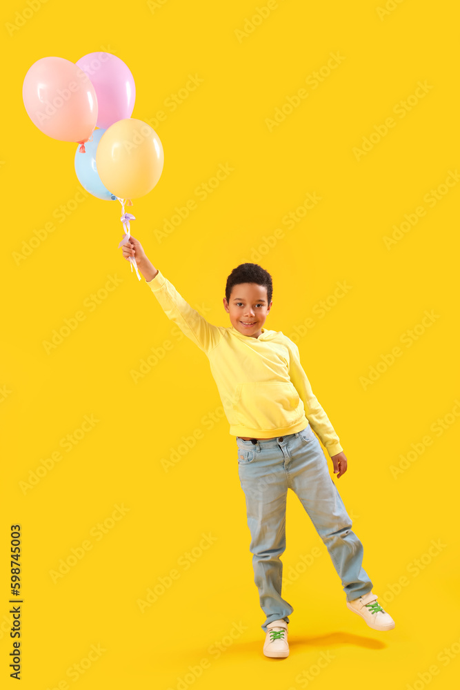 Little African-American boy with balloons on yellow background. Children's Day celebration