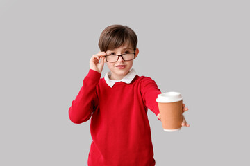 Little boy with cup of cocoa on light background. Children's Day celebration