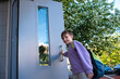 child opens the door to the entrance of a residential building