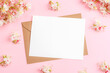 © Viktoriya - Envelope with blank card, white chestnut flowers on pink background. Greeting card. Top view, flat lay, mockup