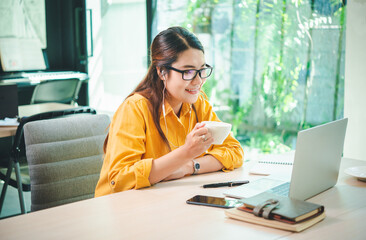 Wall Mural - business woman sits working online on a laptop computer in a cafe.