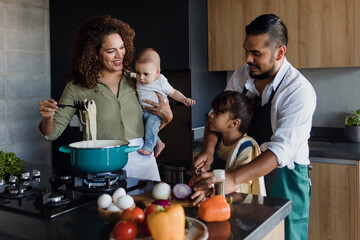 latin family cooking together with children daughter and son in kitchen at home in mexico latin amer