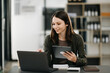 © Nuttapong punna - Beautiful woman using laptop and tablet while sitting at her working place. Concentrated at work.