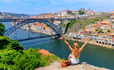 Wall Mural - woman touristwith arms raised enjoying beautiful panoramic view of famous iron bridge and old town- 