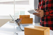 © Witoon - starting a small business SME business owner Asian male entrepreneur working from home check order online Prepare to pack boxes for sale to customers. Business ideas for sme online.