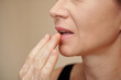© DragonImages - Mature woman applying nourishing balm on her dry lips