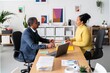 © Studio Marmellata - Side view of smiling Ethiopian woman and man in smart casual clothes talking while looking at each other in modern office