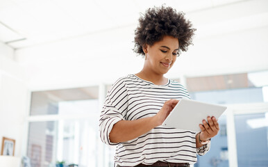 Canvas Print - Making use of online tools to further her ambitions. a young businesswoman using a digital tablet in an office.