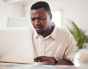 Wall Mural - What is happening now...a young businessman looking confused while using a laptop in an office.